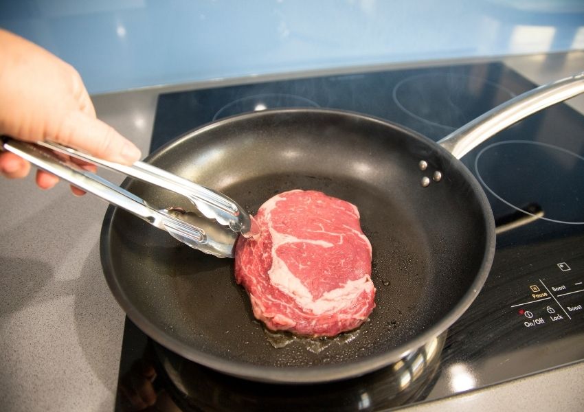 cooking medium-rare steak in pan